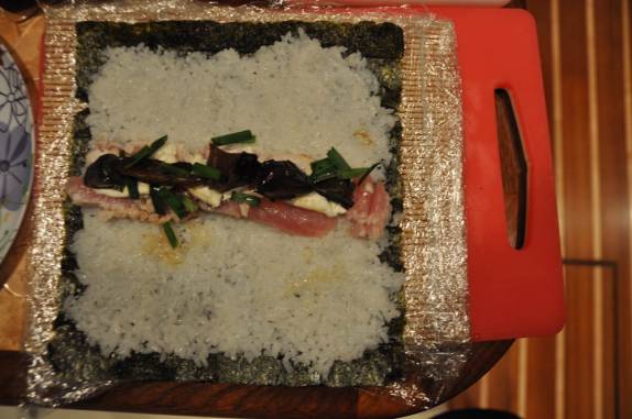 '>Ritual de preparação de sushi. Passo 3: Colocar o recheio de peixe, shitake e cream cheese bem no meio da alga com arroz    (Cidade do Panamá)</